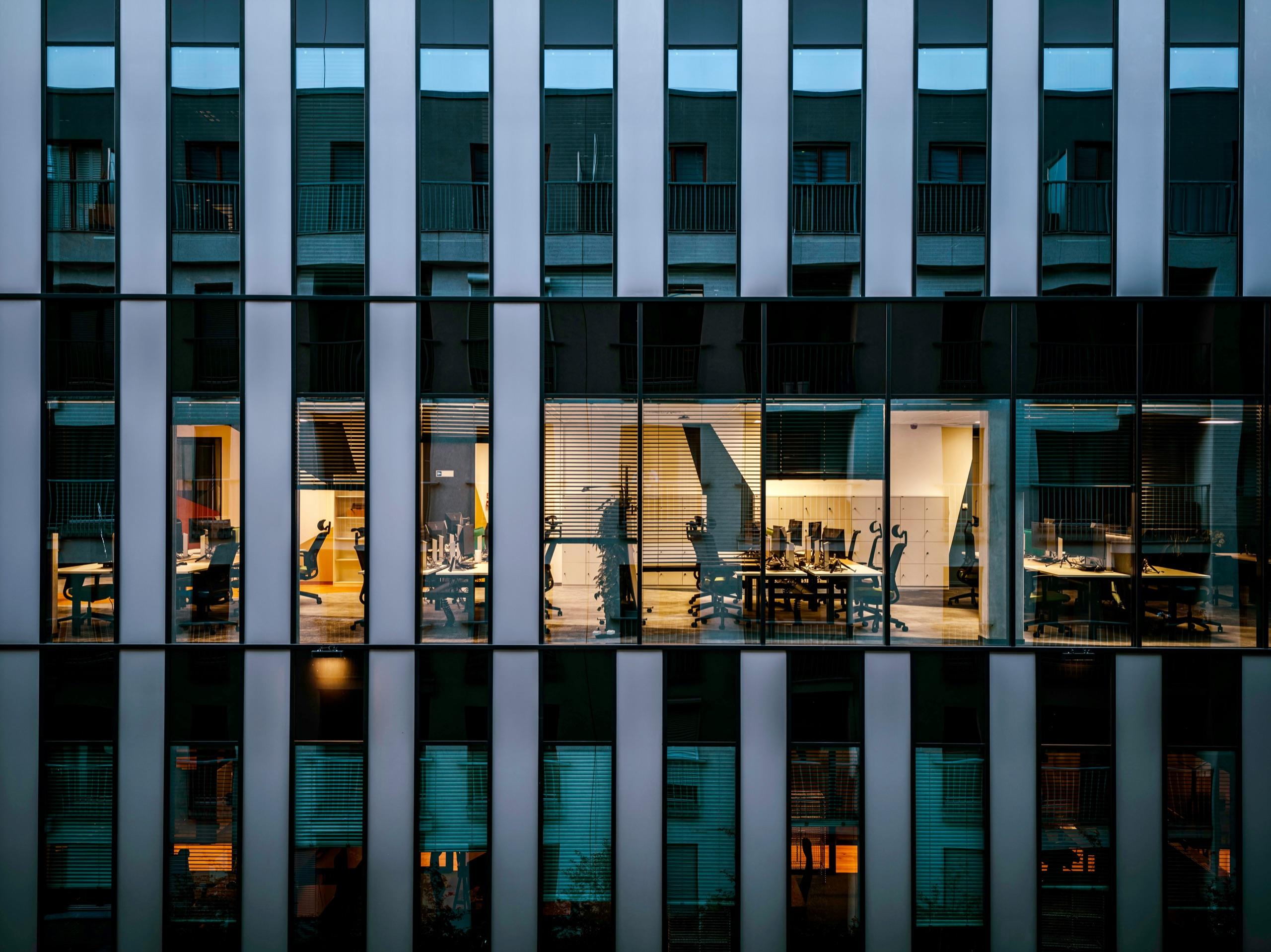 Fachada de un edificio de oficinas de noche, con un piso iluminado